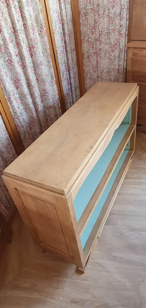 Buffet long ouvert pied moustache. Fond repeint dans une couleur verte douce. Protégé par un vernis mat incolore.