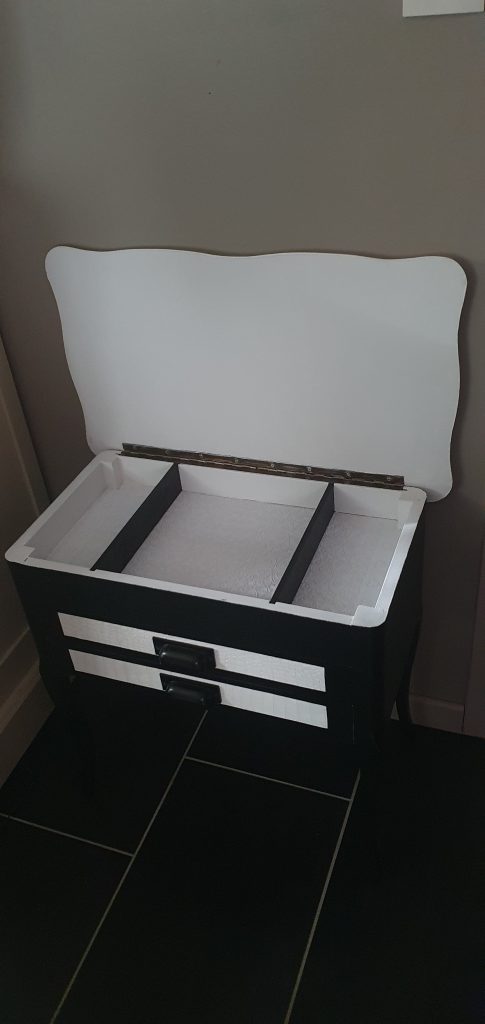 Meuble bas 2 tiroirs et plateau qui s'ouvre. Entièrement refait et peint en blanc et noir. Façades des tiroirs retapissés avec un papier peint blanc imitation croco. Pochoir pissenlit sur le côté gauche pour un touche de fantaisie et poésie.