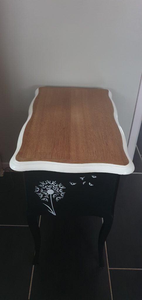 Meuble bas 2 tiroirs et plateau qui s'ouvre. Entièrement refait et peint en blanc et noir. Façades des tiroirs retapissés avec un papier peint blanc imitation croco. Pochoir pissenlit sur le côté gauche pour un touche de fantaisie et poésie.